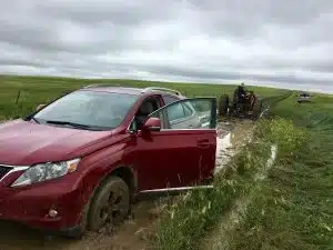 Red SUV Stuck in Muddy Field Being Rescued by Tractor