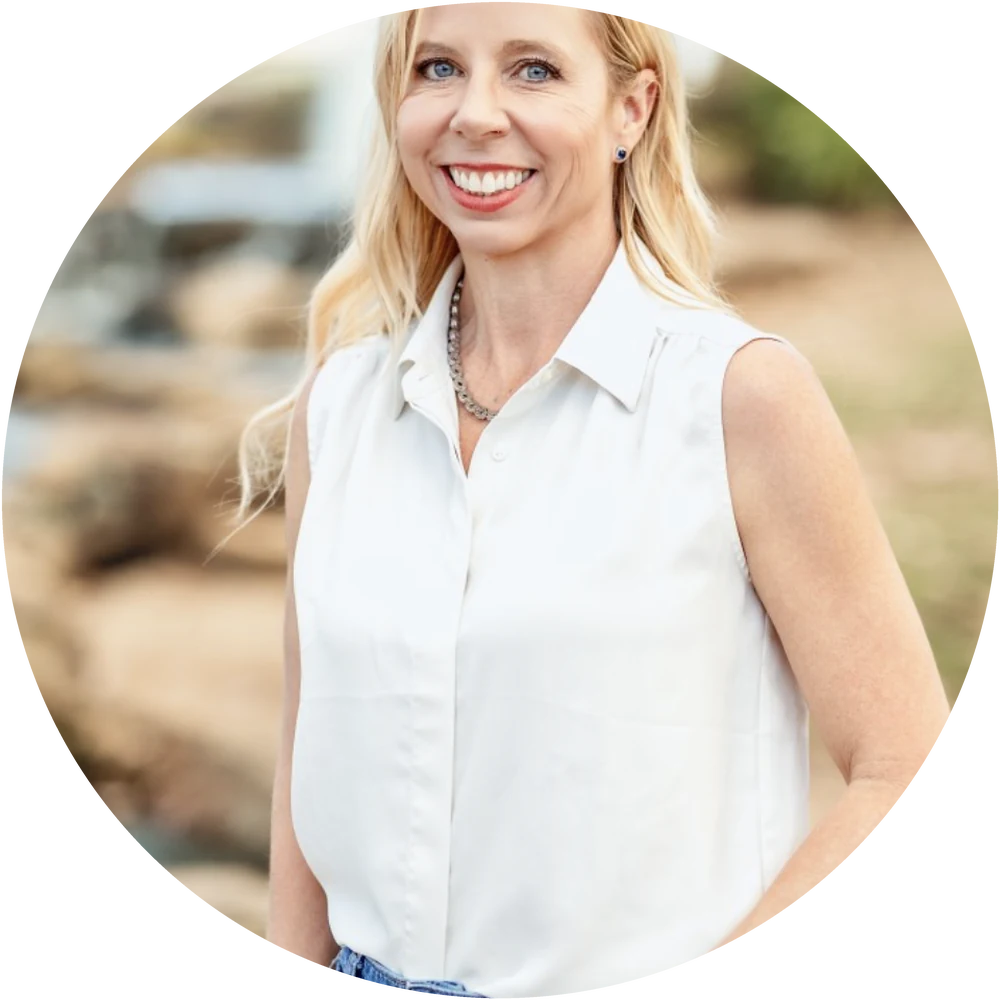 Suzie Glassman, coach and trainer, smiling outdoors in a white sleeveless shirt